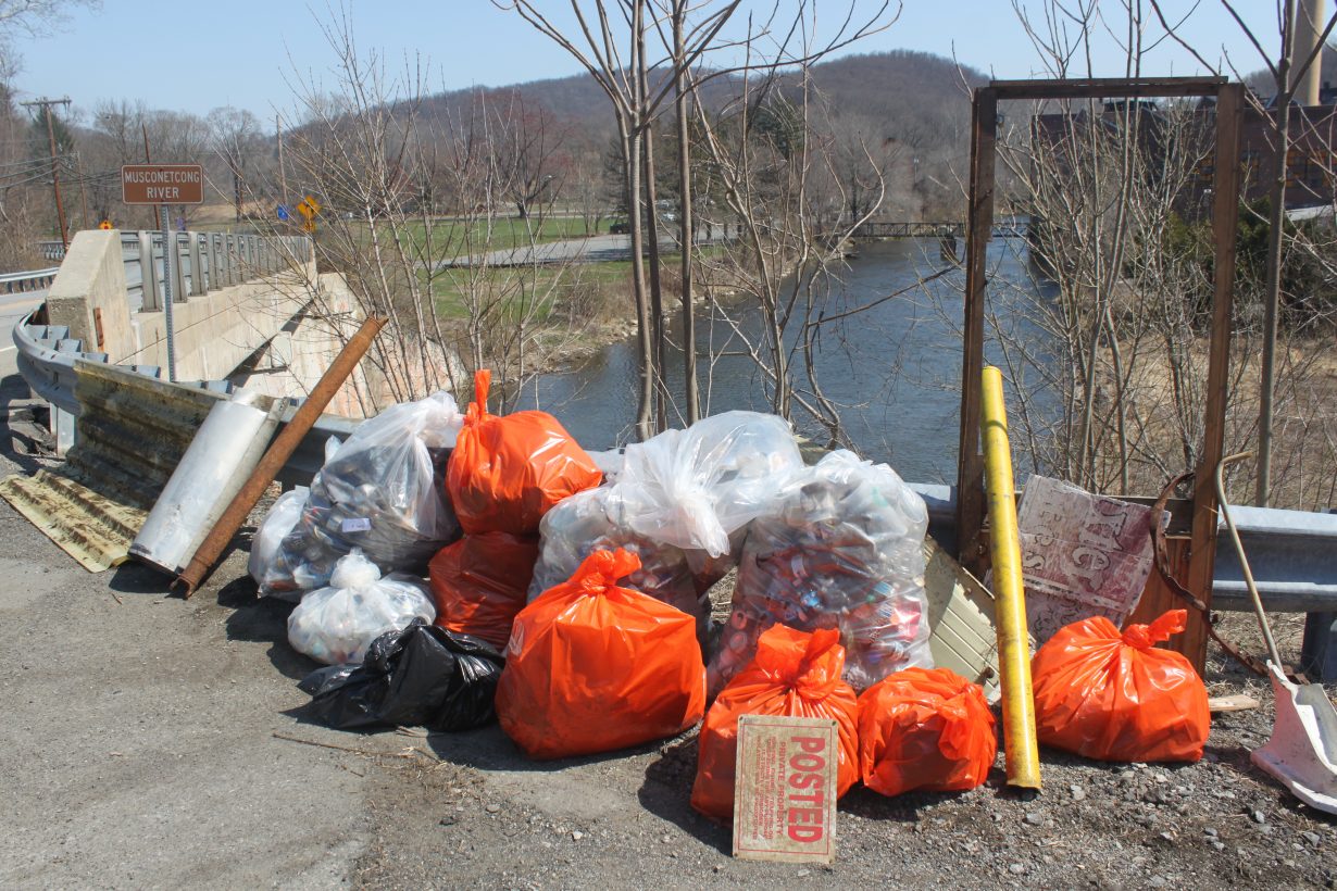 Trash collected during volunteer event with Musconetcong River in the background