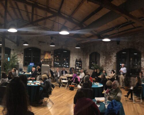 Panoramic image of Princeton Hydro's office space during an evening event. Round tables and chairs filled with people networking.